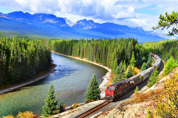 A luxurious train passing through the Canadian Rockies with a view of a blue lake.